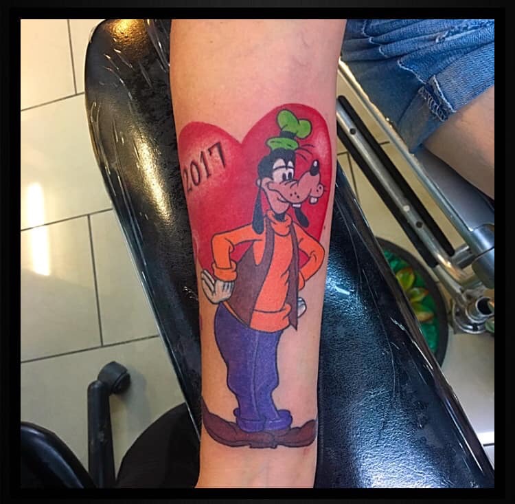 Full-body cartoon artwork of Goofy tattooed on a leg