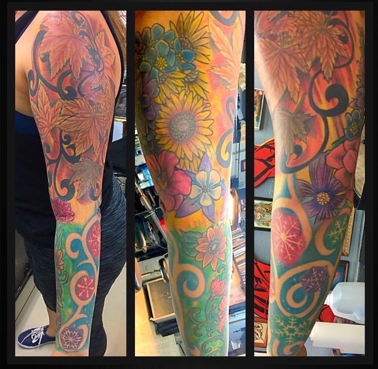 Full-arm tattoo of sunflowers, orchids, and other floral art