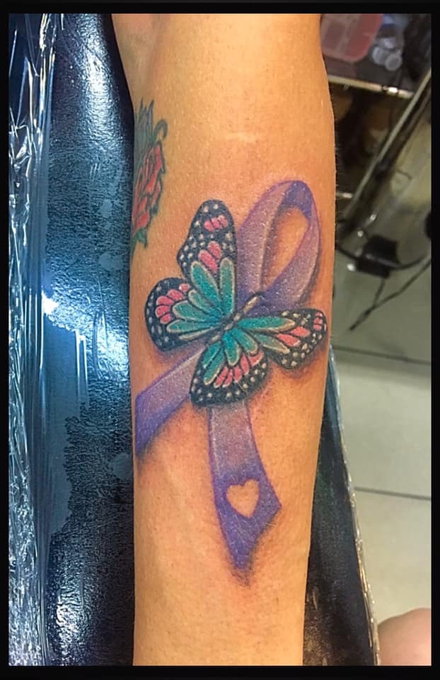 Butterfly landing on a ribbon tattooed on the forearm